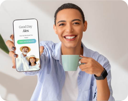 A person holding a smartphone displaying a greeting message and an elderly couple's photo while smiling and holding a mug.